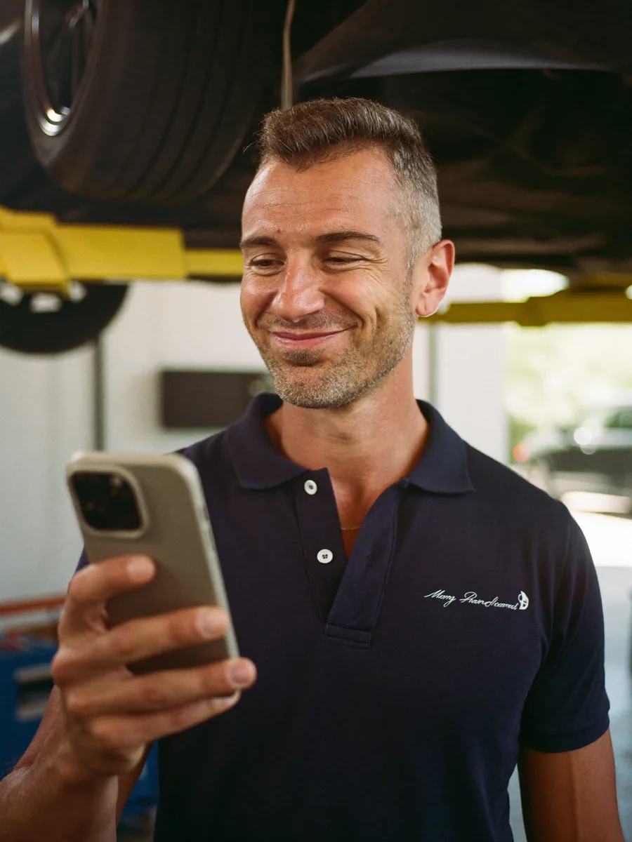 Australian mechanic checking a Motara service reminder on his phone in the workshop